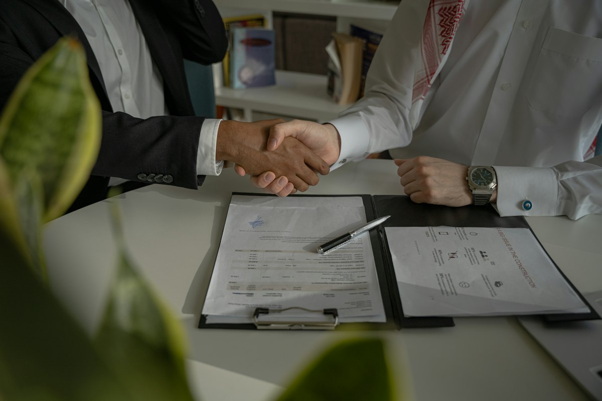 Two people shaking hands over a document